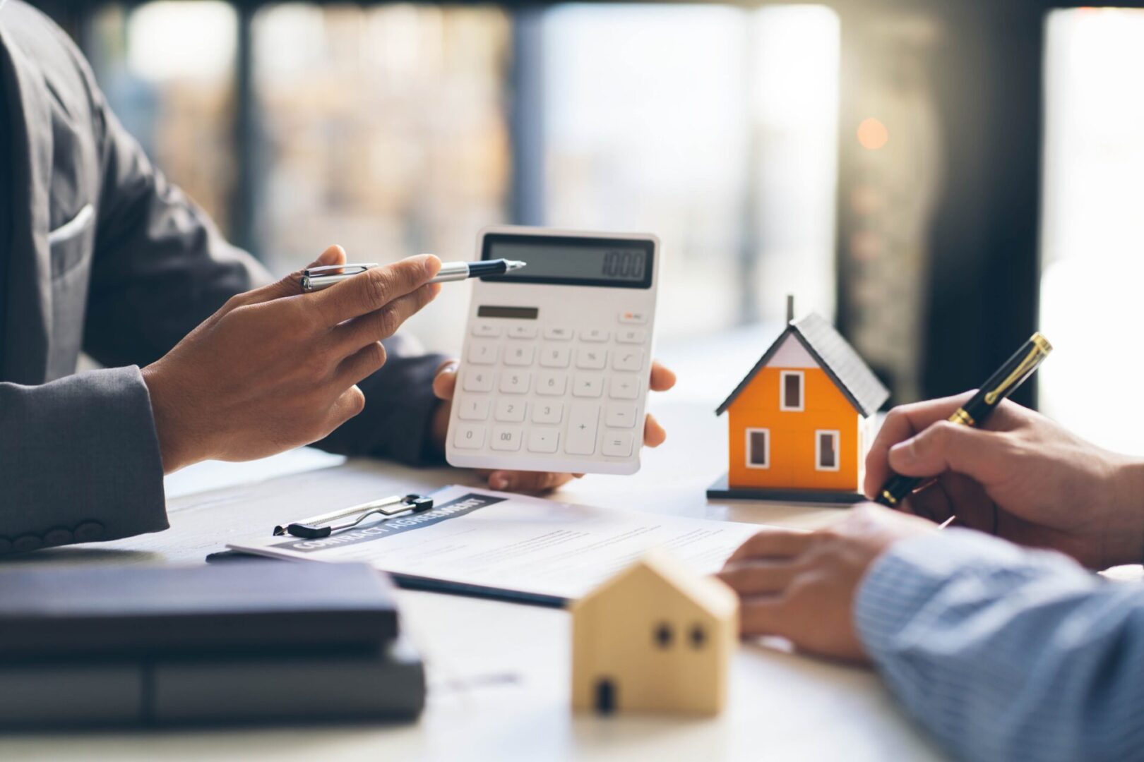 Two people discussing mortgage options with calculator and house models.