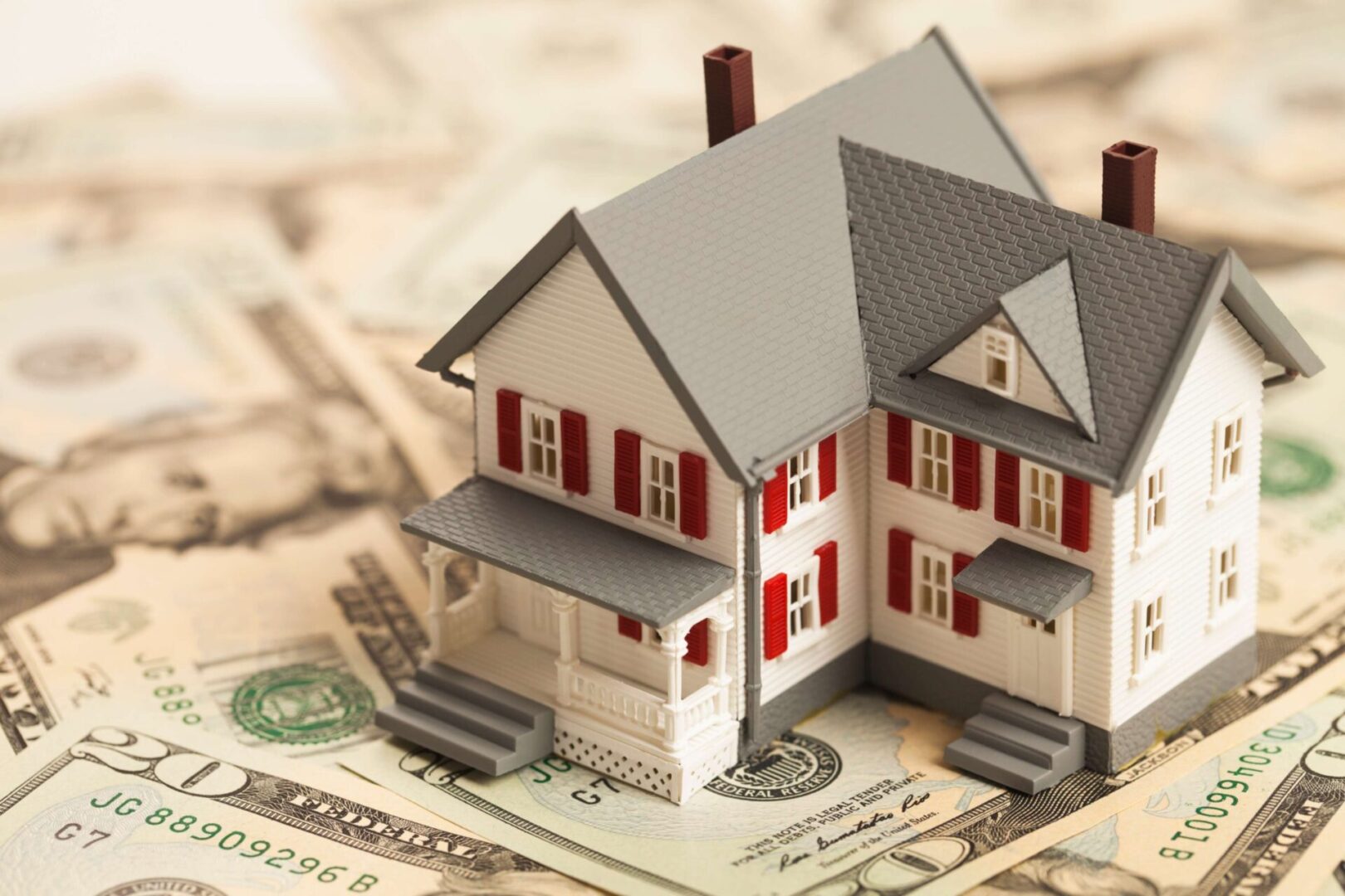 A model house on US dollar bills symbolizing real estate investment.